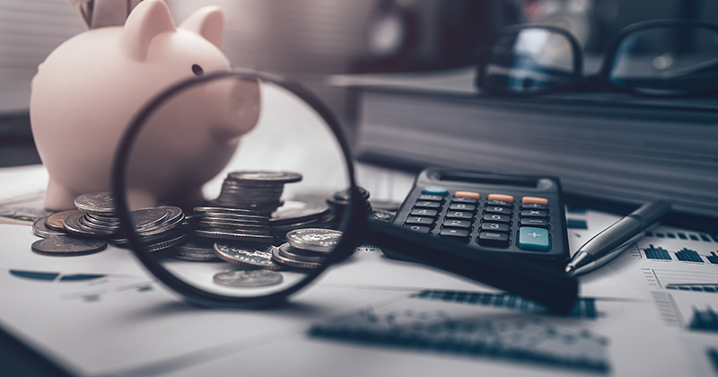 Piggy bank and money bill, magnifying glass view coin for saving money. Calculator, pen, business graph and folder in workplace. Business and finance concept_AdobeStock_578209635.jpeg