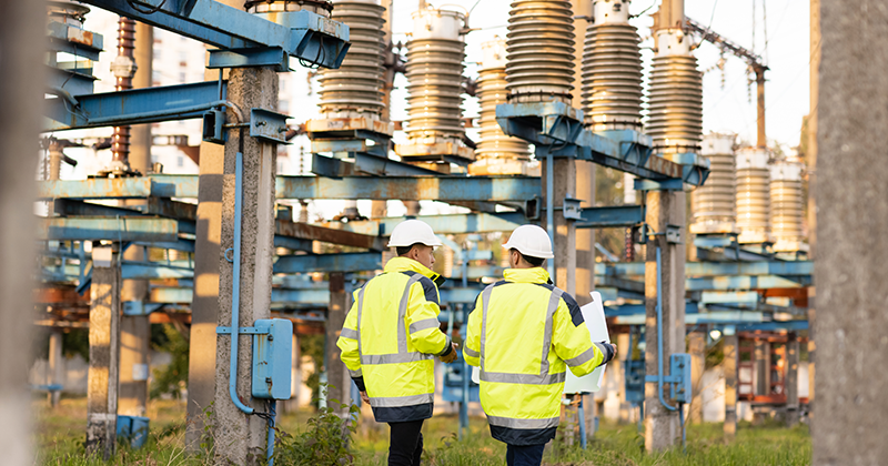 Engineers men in warm clothes use digital tablet computer discuss work walking against power electric substation_AdobeStock_462892459.jpeg