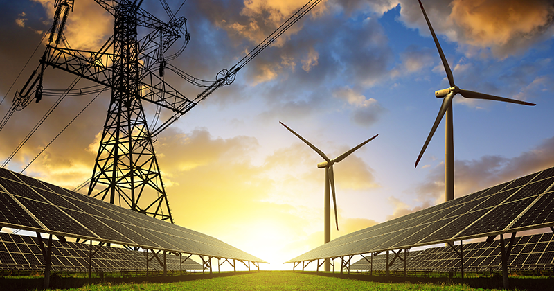 Solar panels with wind turbines and electricity pylon at sunset_AdobeStock_96622127.jpeg