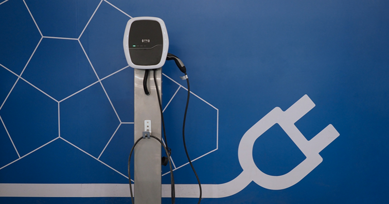 EV charging port with blue wall and plug graphic_Canva.png