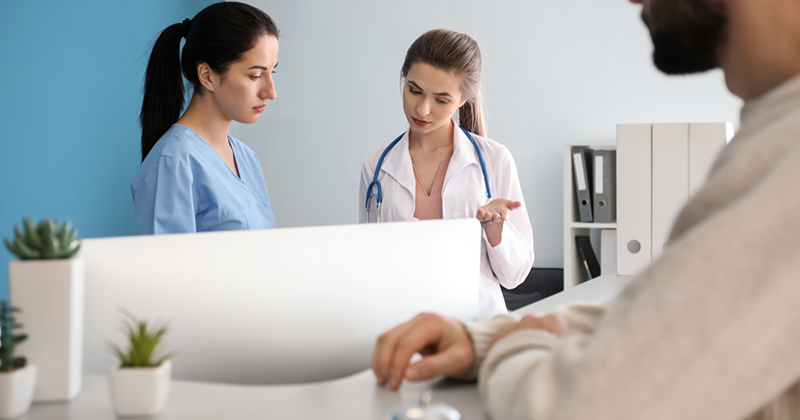 two nurses speaking with patient waiting.png