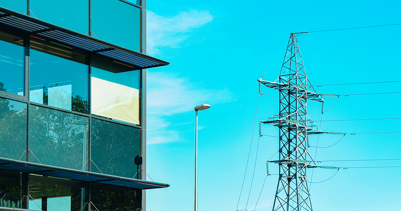 tranmission tower beside a modern building with blue sky_Canva.png