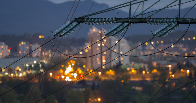 power lines in front of a city skyline at dusk